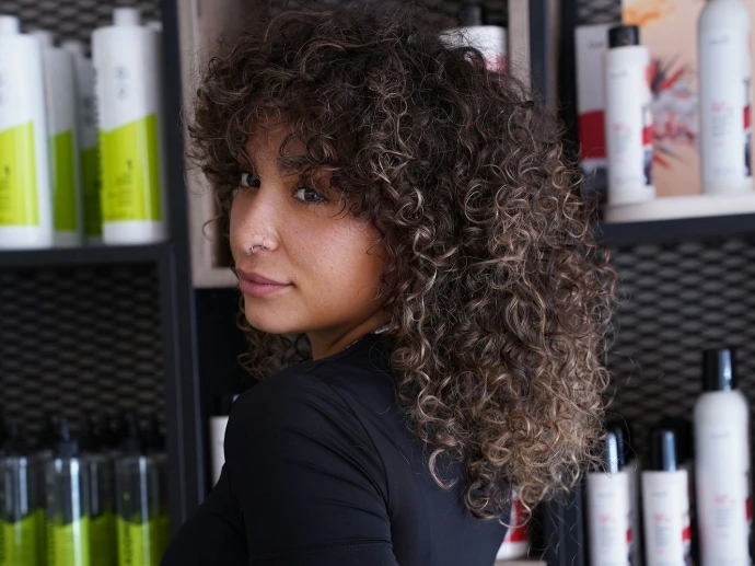 A woman standing in front of a shelf of hair products